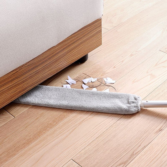 Dust brush being used to clean under an item of furniture
