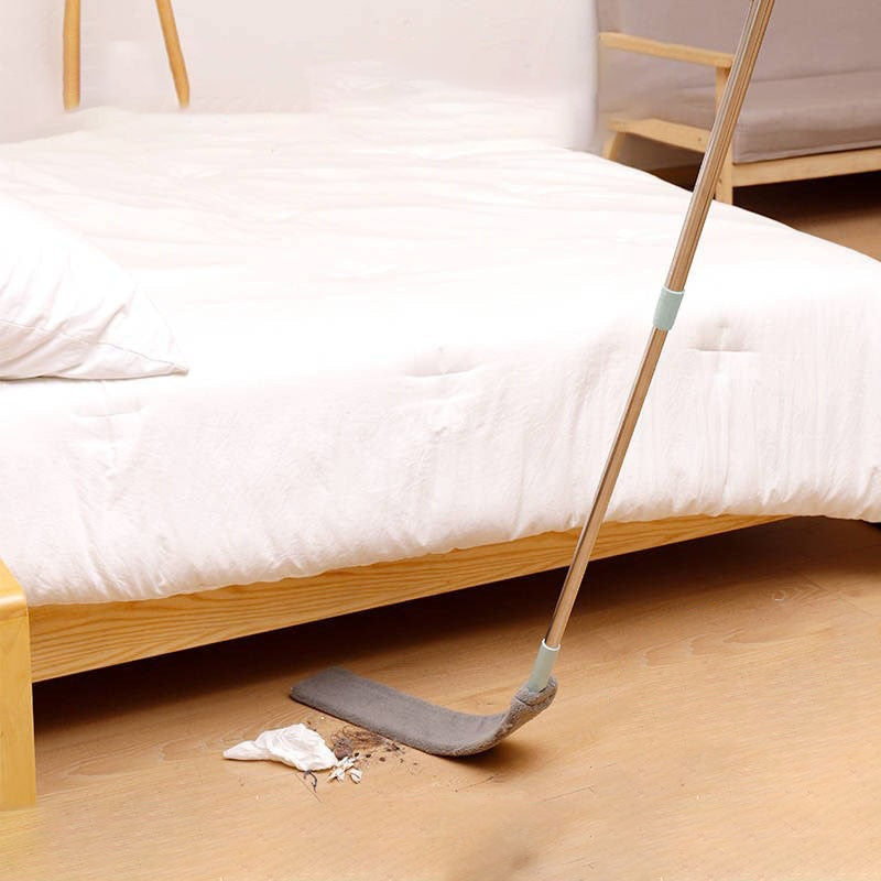 Dust brush being used to clean underneath a bed