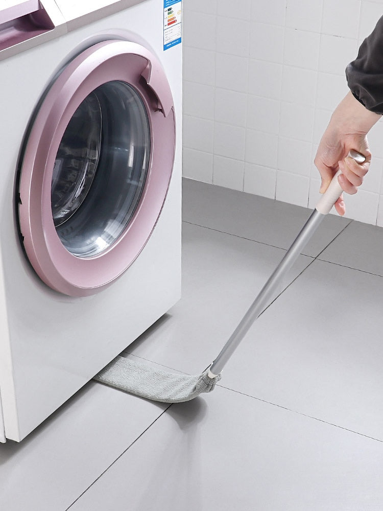 Dust brush being used to clean underneath a washing machine